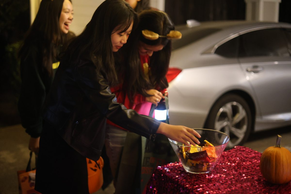 Students Annie Liu ('27), Savannah Stoehr ('27), and Emma Luey ('27) excitedly look for their favorite treats offered during the spooky season. 