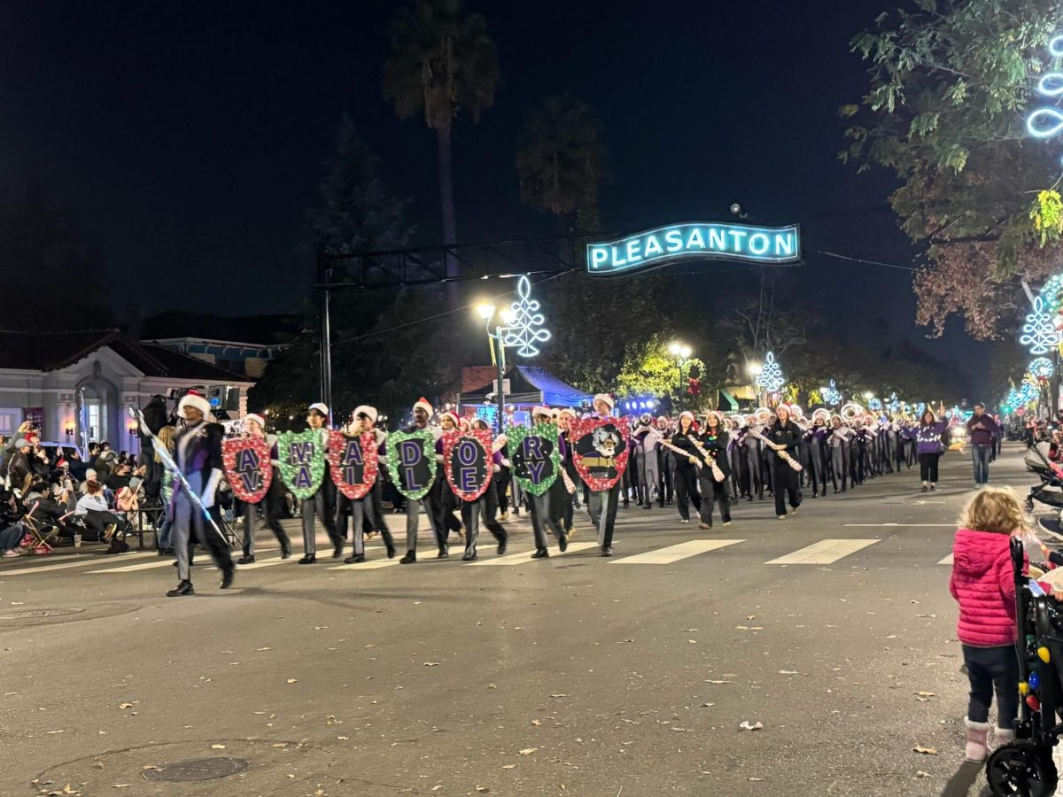 As the band makes their entrance, they hold signs representing Amador Valley. They play as they walk down, the bright Pleasanton sign above them.